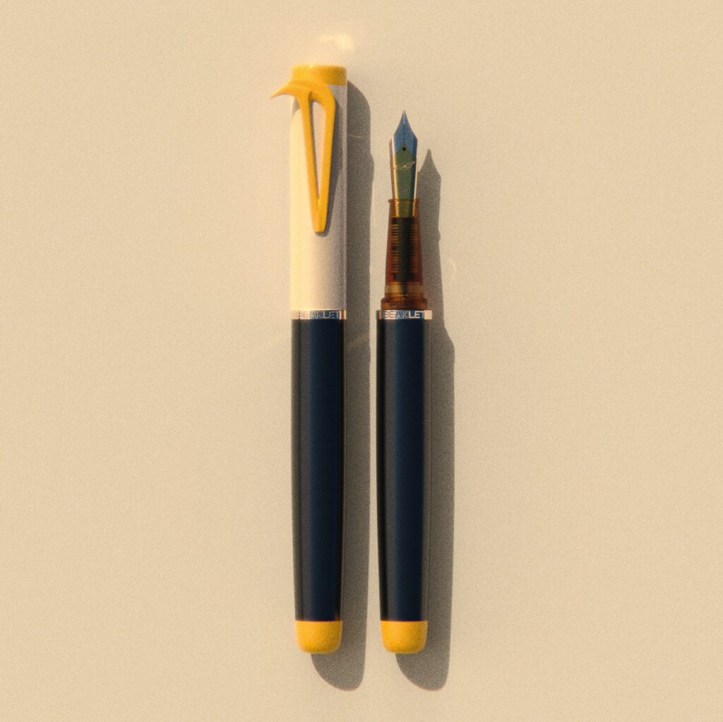 Beaklet The Hornbill writing instrument, capped and uncapped, with an ivory cap, black barrel and yellow beak-shaped clip.