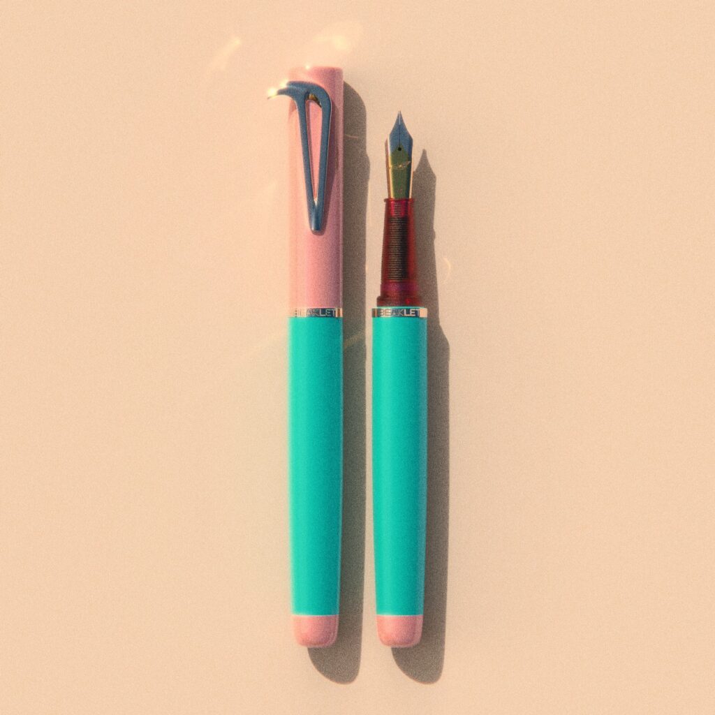 Beaklet Miami writing instrument, capped and uncapped, with a pink cap, aqua barrel and pink end detail.