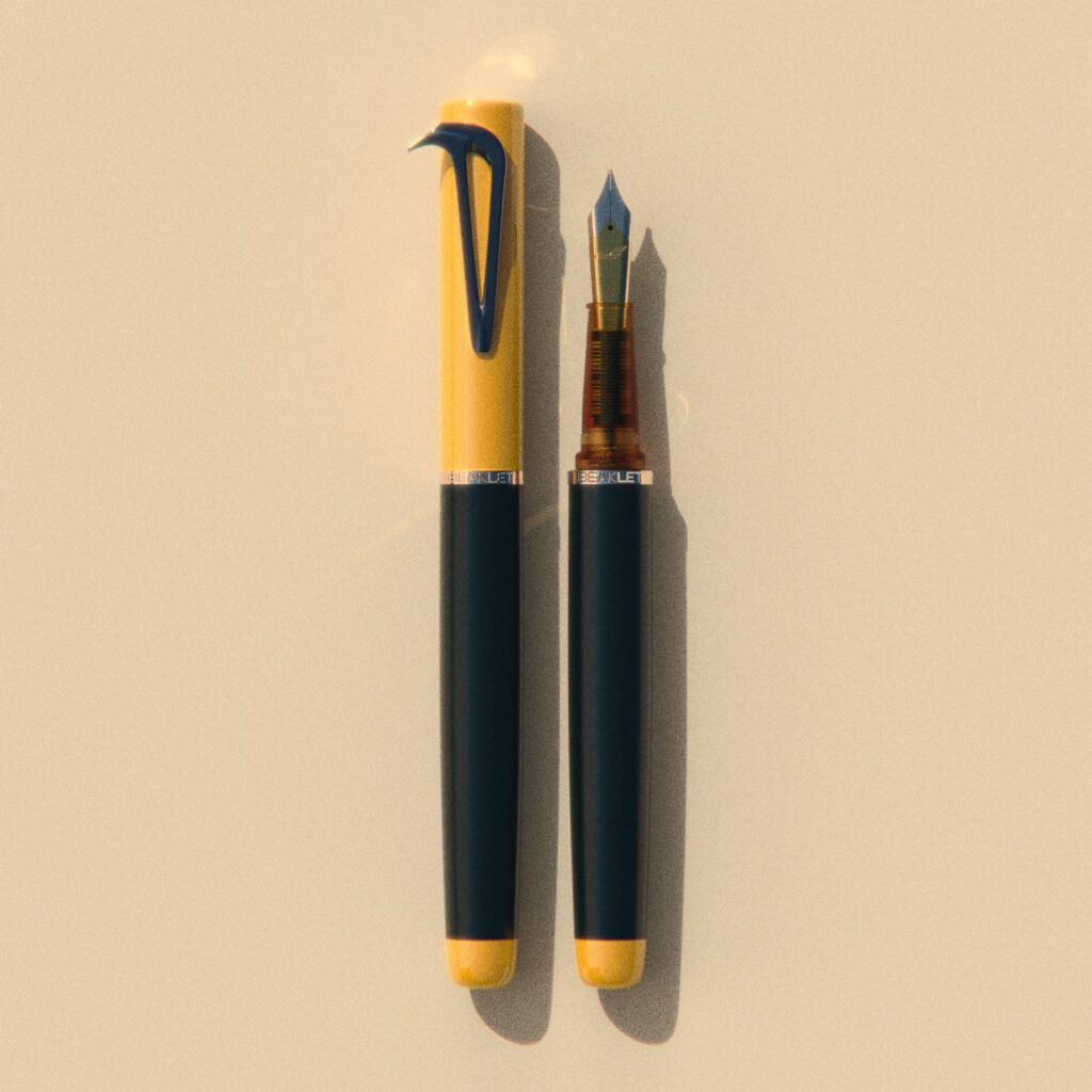 Beaklet Mumbai Kaali Peeli writing instrument, capped and uncapped, with a yellow cap, dark barrel and dark beak-shaped clip.